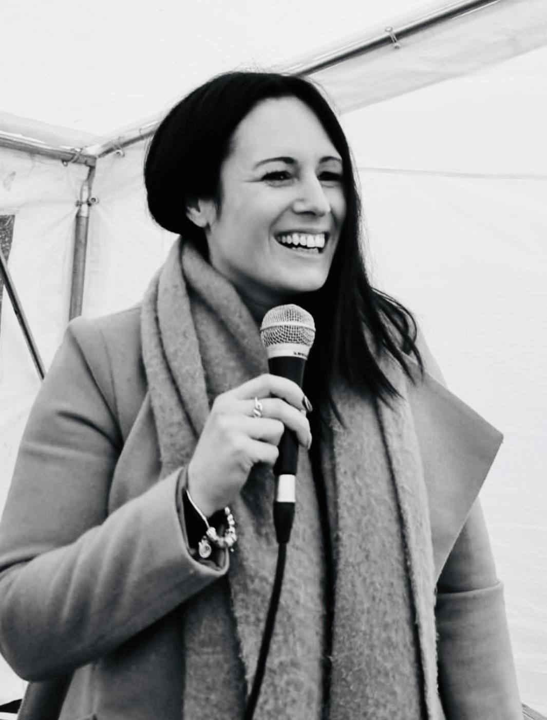 Black and white photo of Sadie laughing with a microphone
